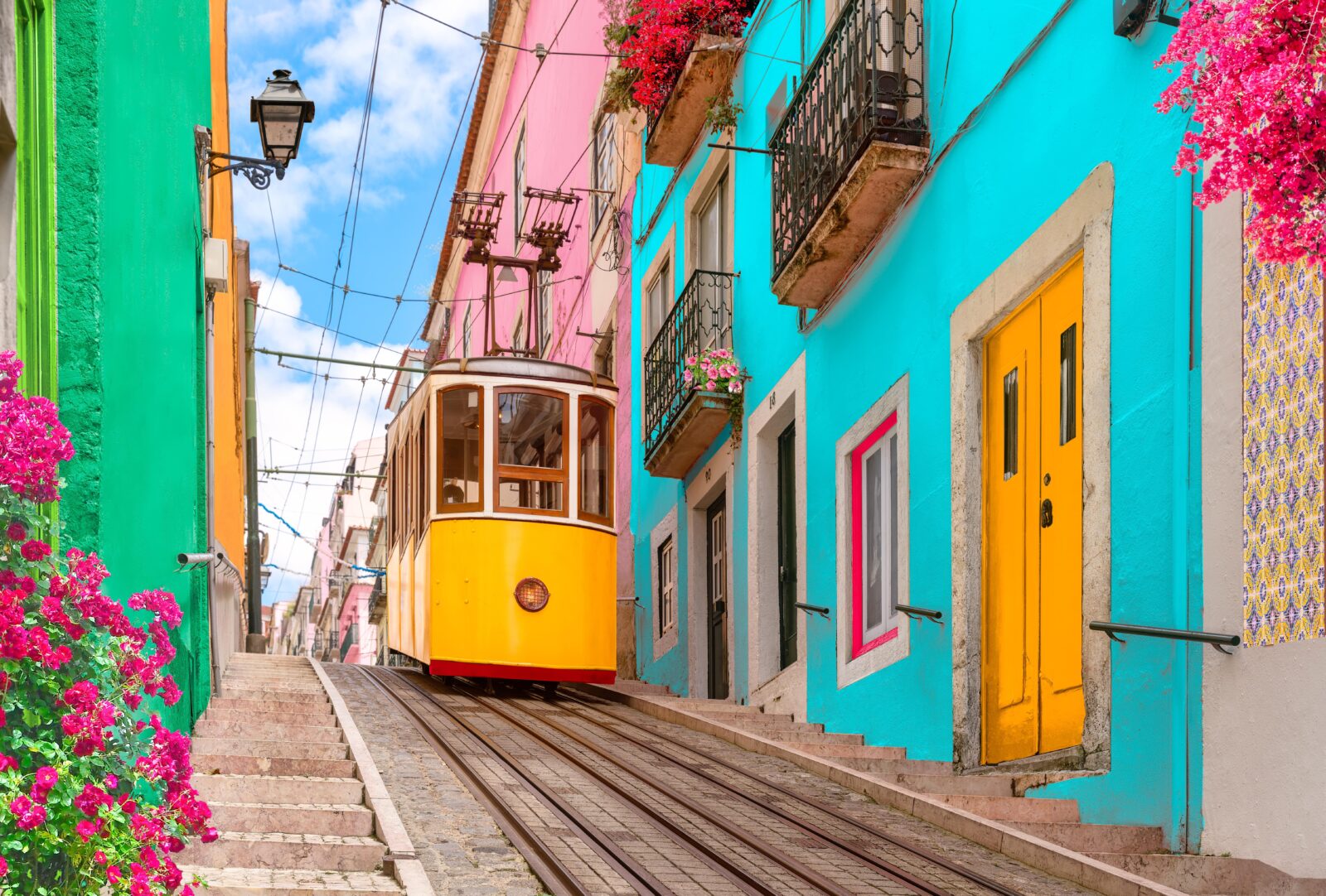 Portugal alleyway with bright buildings and an orange trolley rolling down rail tracks