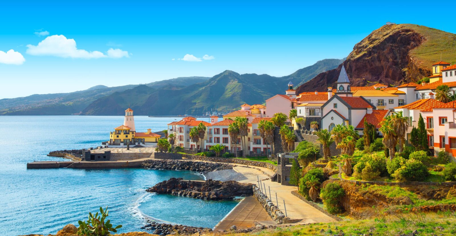 Sunny costal Portugal with clear blue water, mountains and orange and white buildings